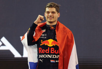 2021年F1阿布扎比大奖赛正赛，身披荷兰国旗在领奖台上握拳庆祝的红牛车手维斯塔潘