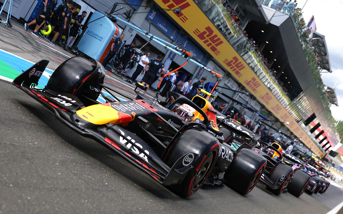 2025年F1奥地利大奖赛排位赛,角田裕毅在维修区通道行驶于维斯塔潘的红牛赛车之前