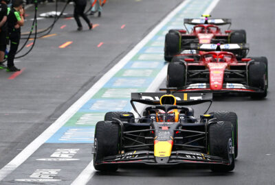 2024年F1比利时大奖赛，维斯塔潘驾驶红牛赛车与法拉利车群在雨中驶过斯帕赛道维修区通道