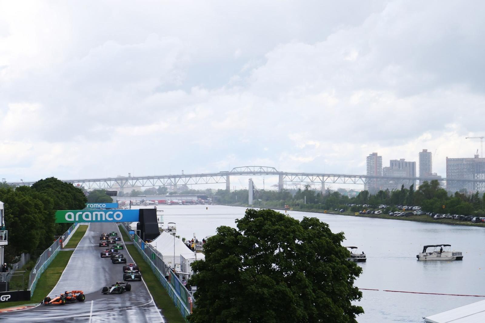 2024年F1加拿大大奖赛正赛，迈凯伦赛车在湿地领跑，后方是圣劳伦斯河与雅克·卡蒂埃桥