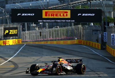 2023年F1新加坡大奖赛三练，维斯塔潘驾驶红牛RB19赛车在黄昏的滨海湾市街赛道通过倍耐力龙门架
