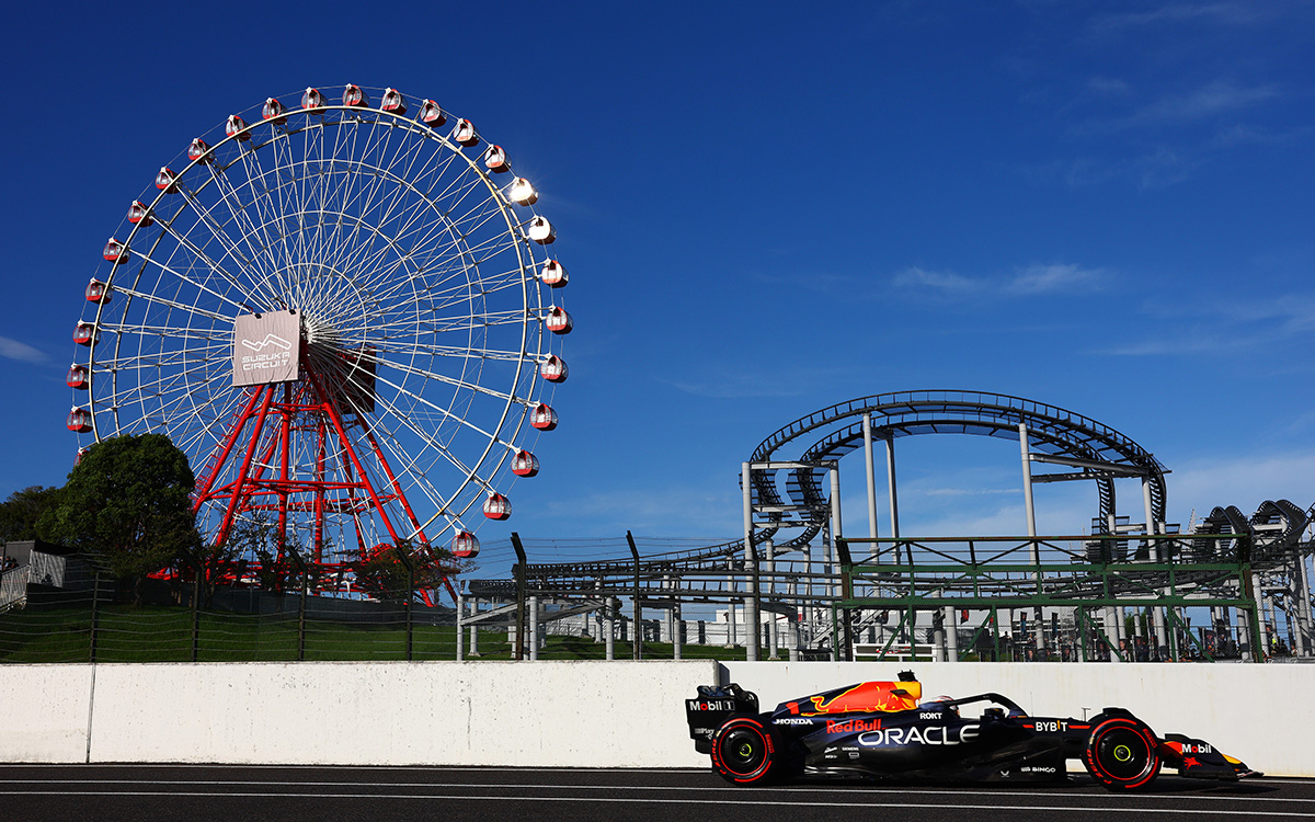 2023年F1日本大奖赛排位赛，维斯塔潘驾驶红牛RB19赛车行驶在铃鹿赛道维修区通道，背景为游乐园摩天轮