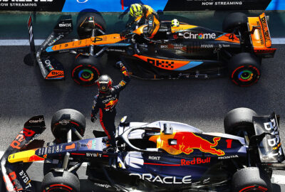 2023年F1圣保罗大奖赛正赛结束后，冠军维斯塔潘站上RB19庆祝，亚军诺里斯在迈凯伦座舱中伸手致意