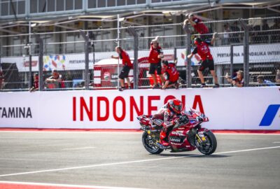 2026年10月10日MotoGP印尼站冲刺赛，马克·马奎斯驾驶93号杜卡迪赛车驶过维修区墙前，车队人员庆祝。