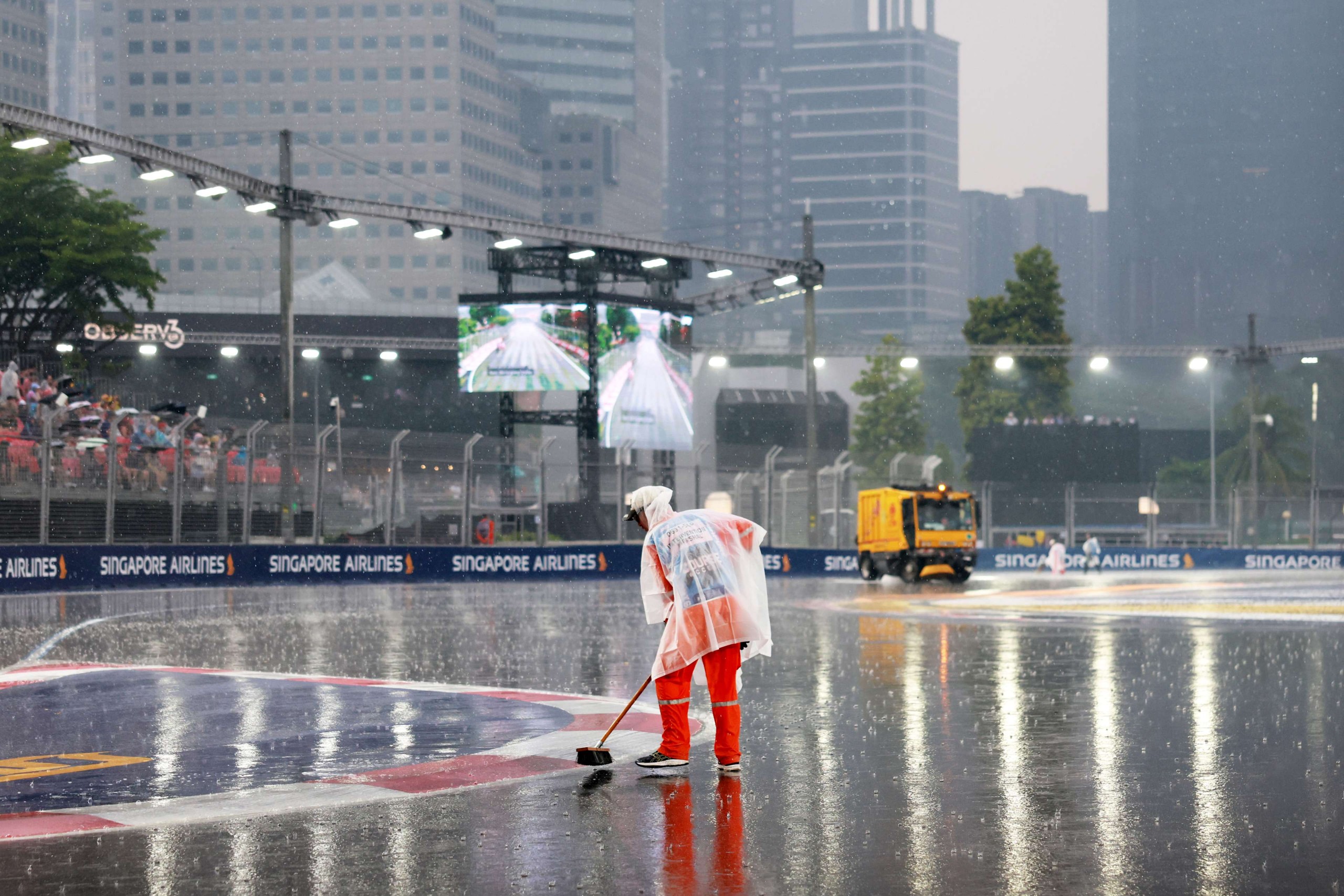 2026年10月10日F1新加坡大奖赛冲刺赛发车前，工作人员清理滨海湾街道赛道积水。