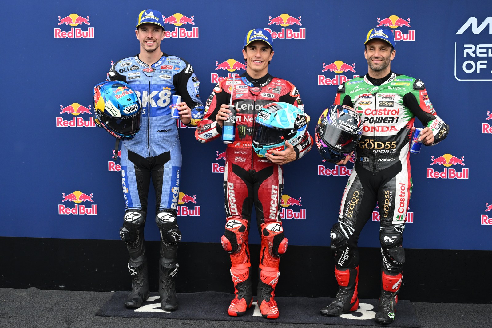 2026年MotoGP澳大利亚站，马克·马奎斯居中，与左侧阿莱克斯·马奎斯、右侧约翰·扎尔科合影。