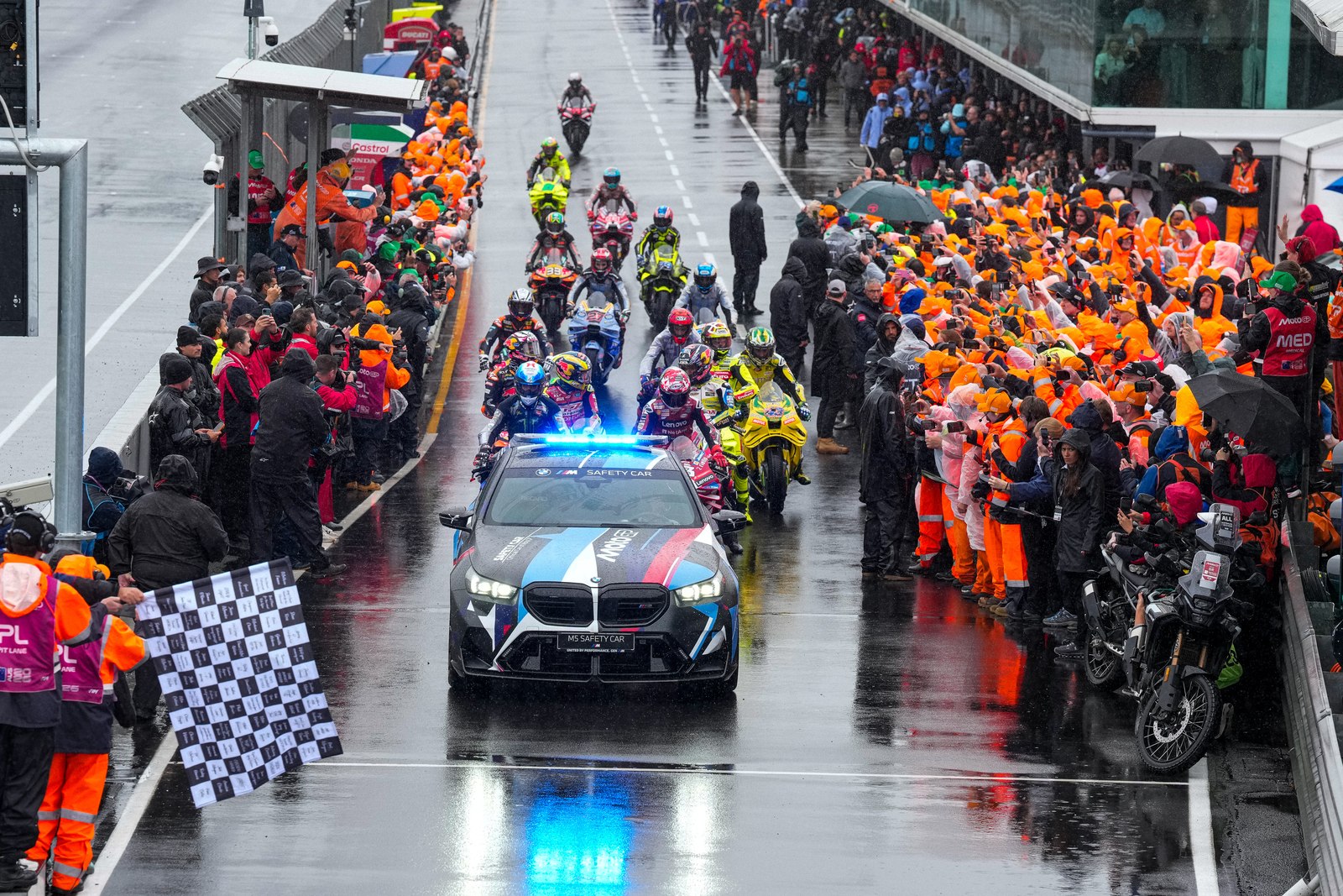2026年MotoGPオーストラリアGPで、雨のピットレーンをセーフティカーに先導されて通過するライダーたち