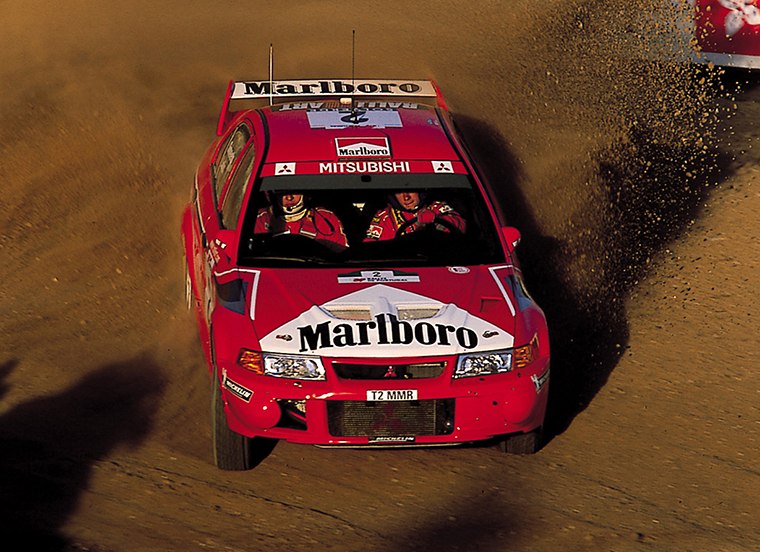 Tommi Mäkinen driving a Mitsubishi Lancer Evolution VI on gravel in an archive photograph from 2000; the specific round is unconfirmed