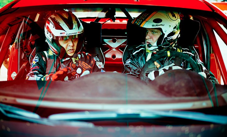 Akio Toyoda and Tommi Mäkinen sitting in a red Mitsubishi Evo, from Toyota's 2015 team-principal appointment announcement