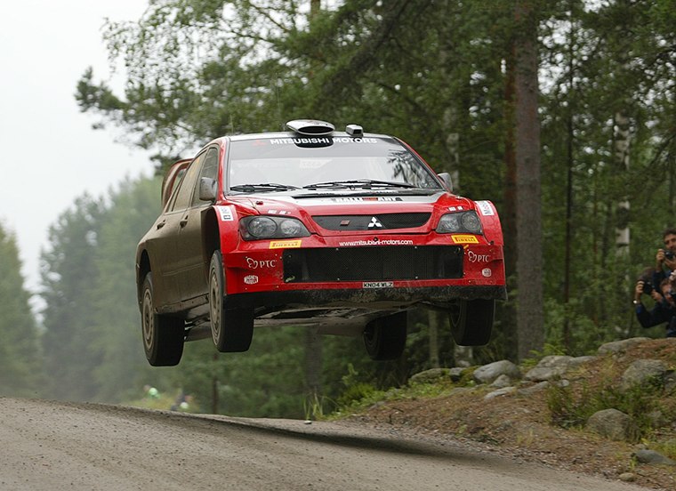A Mitsubishi Lancer WRC05 jumping on a gravel road, from the 2005 factory-team archive; the specific round and crew are unconfirmed