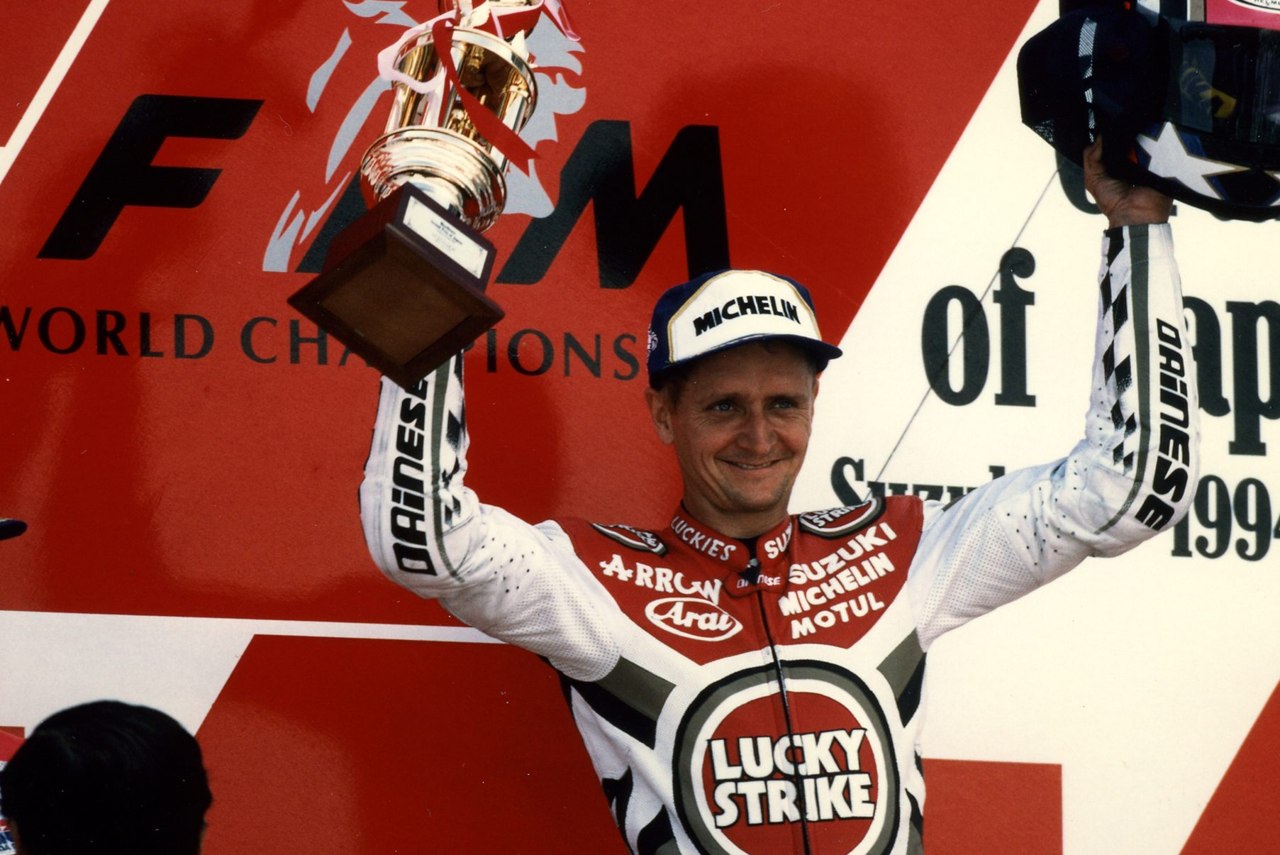 Kevin Schwantz raises a trophy in celebration, in an archive photograph from Suzuki Press; the specific round is unconfirmed