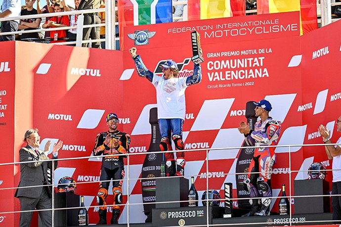 Alex Rins celebrates on the podium at the 2022 Valencian Grand Prix, alongside Brad Binder and Jorge Martín