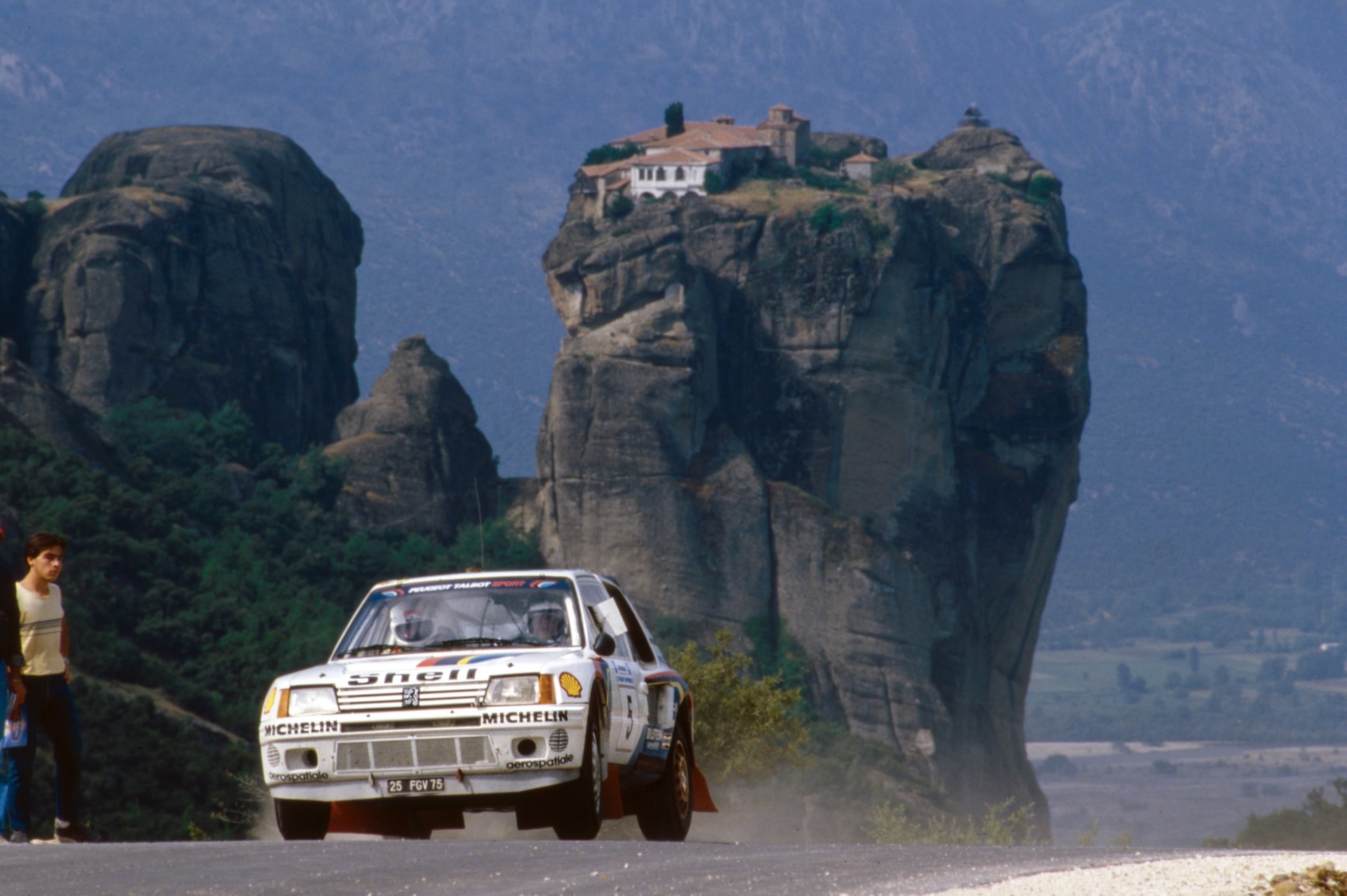 A Peugeot 205 T16 crossing rocky mountain terrain at the 1985 Acropolis Rally.