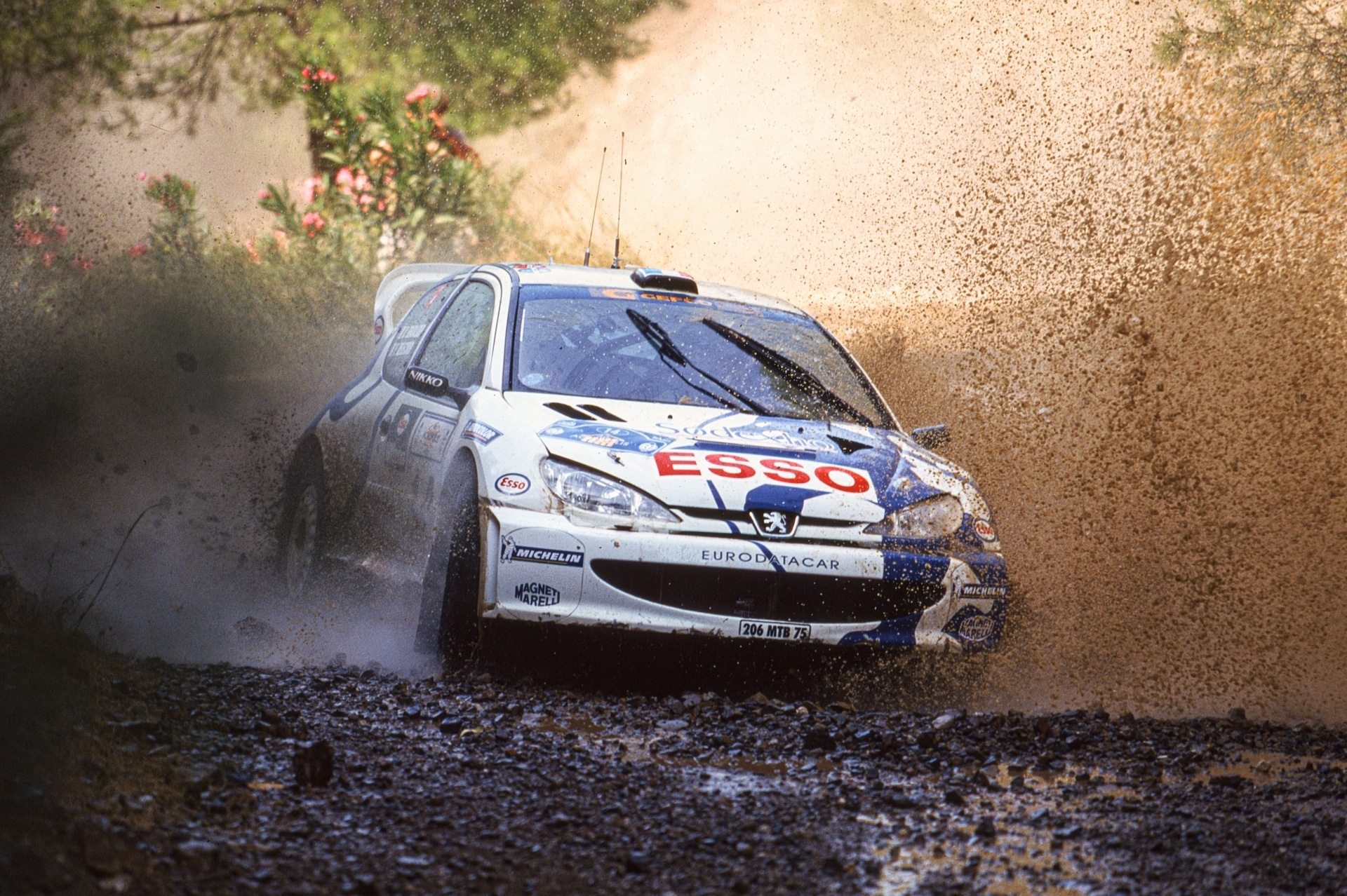 Delecour's Peugeot 206 WRC crosses standing water at the 1999 Acropolis Rally.
