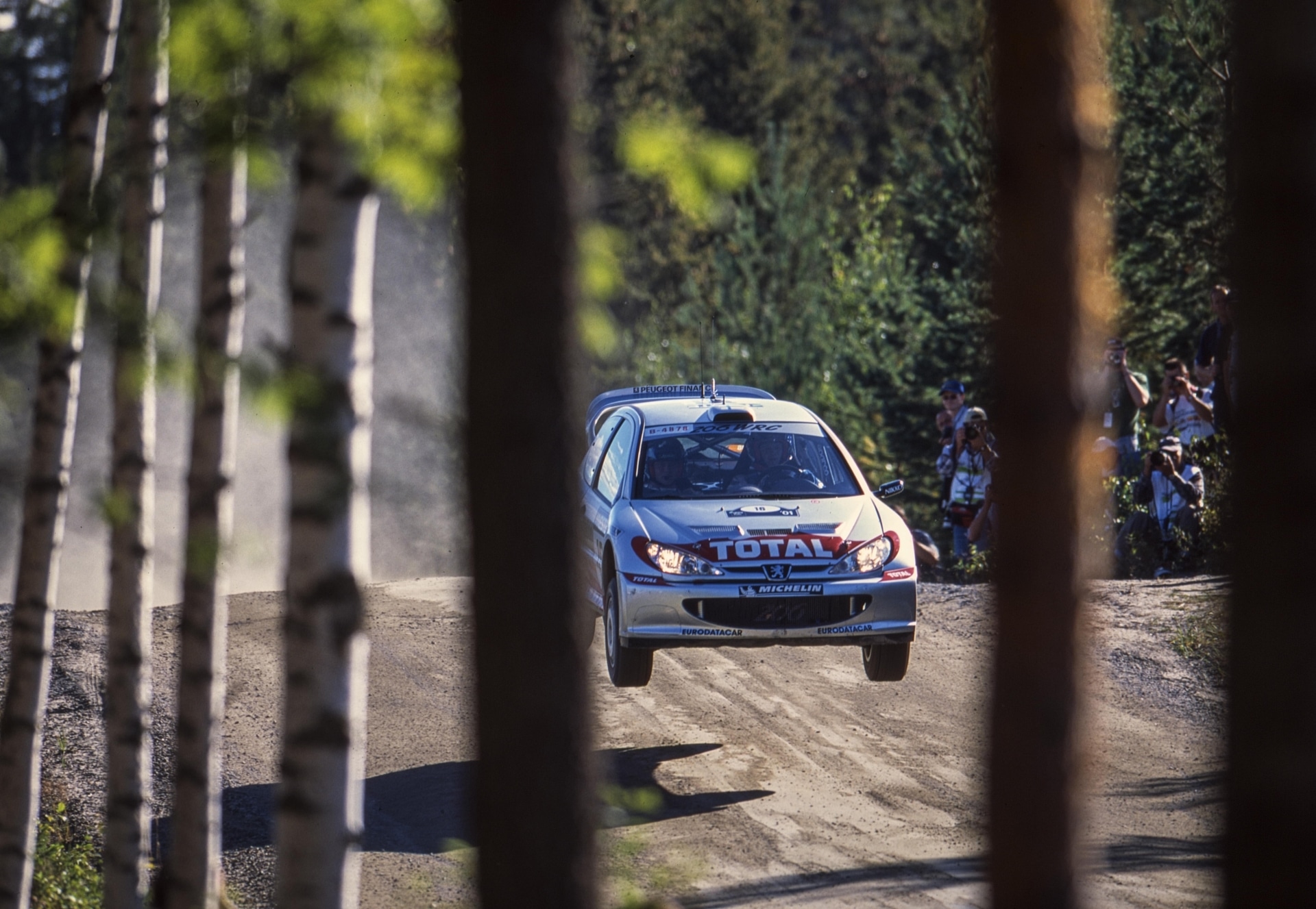Grönholm's number 1 Peugeot 206 WRC airborne among the trees at the 2001 Rally Finland.